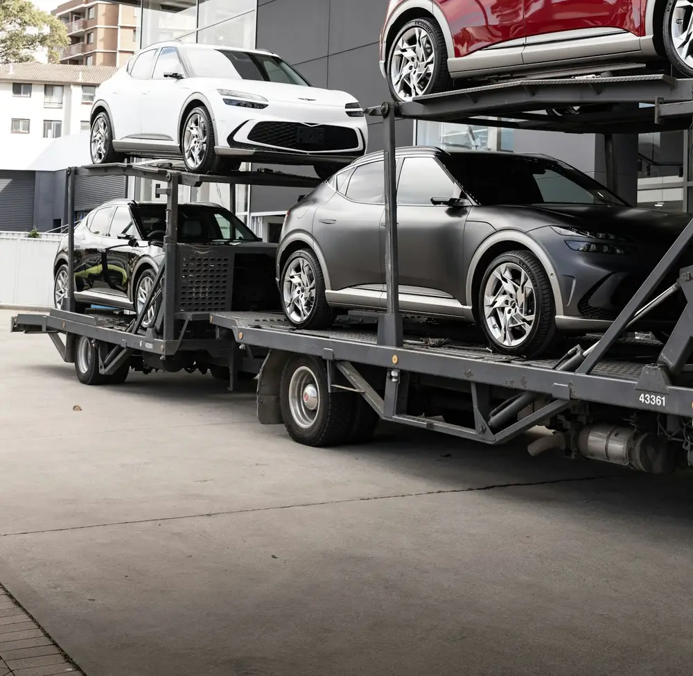Car carrier loaded with new vehicles outside a dealership
